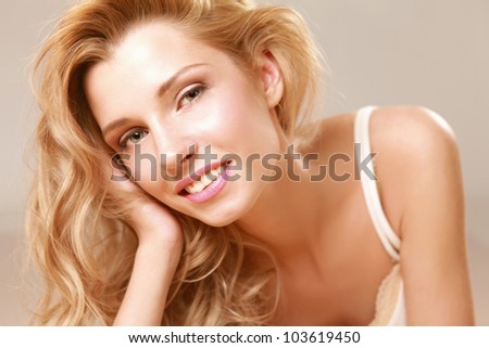 A beautiful smiling woman lying on bed, isolated on grey