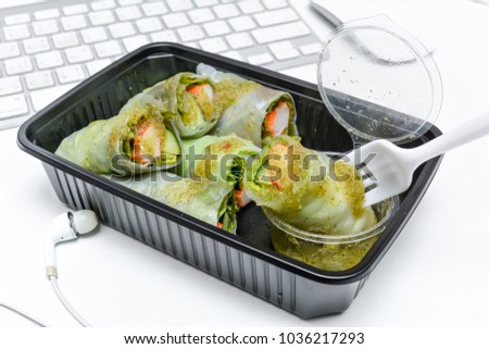 Spring roll, Salad box asian style fast food with green fresh organic vegetables mixed lettuce, seaweed, Japanese cucumber, crab stick and spicy seafood sauce in plastic box on work table ready to eat