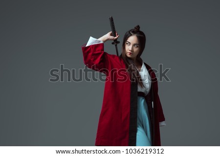 samurai in kimono holding katana sword and looking away isolated on grey Royalty-Free Stock Photo #1036219312