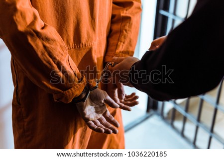 cropped image of prison officer wearing handcuffs on prisoner Royalty-Free Stock Photo #1036220185