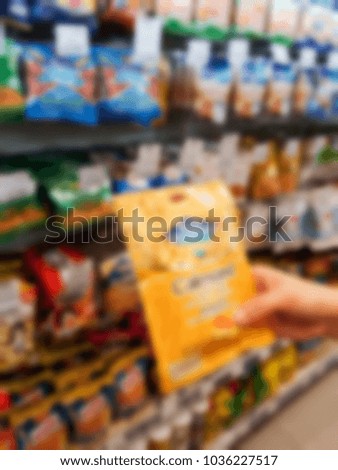 Shopping at supermarket By a hand is holding a goods. It's blurred picture.