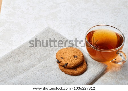Top view close up picture of tea in transparent cup with chocolate chips cookies on a cotton napkin on white background