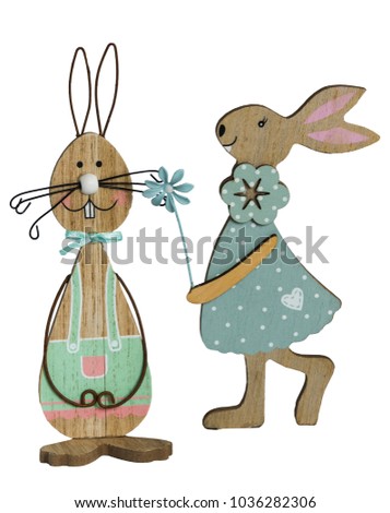 Two wooden Easter bunnies with painted decoration and parts of wire in front of a white background