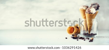 Chocolate and coffee ice cream in waffle cone with coffee beans on grey stone background. Summer food concept, copy space. Healthy gluten free ice-cream. Banner
