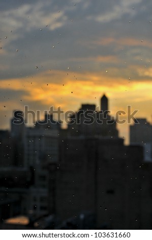 rain drops at window with unfocus manhattan skyline at sunset