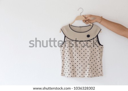 Closeup of Hands holding natural color blouse on white background.