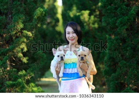 Cute little French bull dog with happy owner playing at the park in summer. Young Asian woman relaxing, having fun, holding the dog to share love and care. Love pet as family.