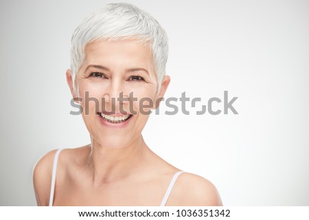 Portrait of beautiful senior woman in front of white background. Royalty-Free Stock Photo #1036351342