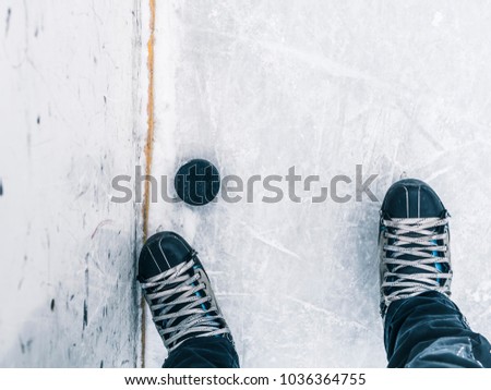 top down view of hockey puck and skates on ice