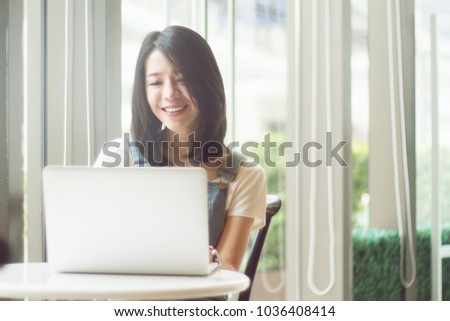 Portrait of cute asian teen woman using a laptops or notebook computer in coffee cafe. bright and light process. selective focus. filtered image and light effect added. happy smile chill out concept