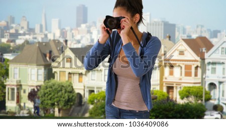 A Latina woman takes pictures of the Painted Ladies in San Francisco