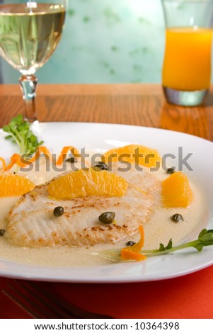 Grilled skate (ray) with orange and caper sauce served with orange juice.