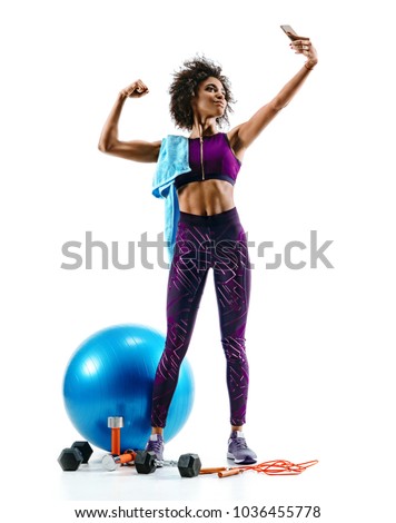 Sporty girl taking selfie pictures on smartphone with sports accesories on white background. Strength and motivation. Full length