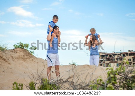 A happy couple, married, husband and wife in the summer vacation. Blue sea. Holiday dream .. On the beach kissing. With two kids, two guys. Mother and father happy. Much sun and sand.