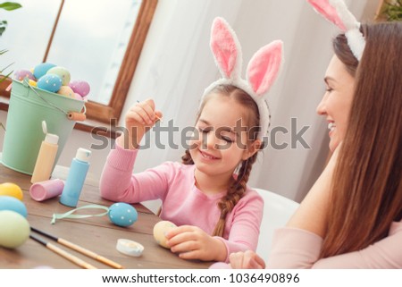 Mother and daughter together easter preparation at home sitting in bunny ears girl holding the brush