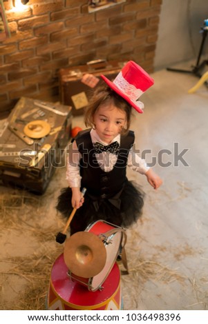 Vintage circus. Smiling funny baby girl in a red hat cylinder  in front of the circus tent.