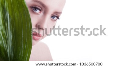 Beauty shoot. European, young, blue-eyed woman posing with green leaf.