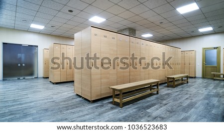 Interior of a locker room. Clean empty dressing room with big lockers and wooden bench Royalty-Free Stock Photo #1036523683