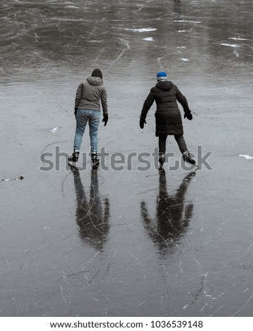 Reflection in the ice of a couple skating on a frozen pond in the 'Haagse Bos' in the Netherlands. 