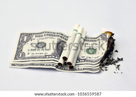 Cigarette on the pile of money It burns money and health concept.