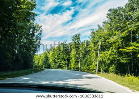 Beautiful Picture of curved road through Lush green forest as taken from car