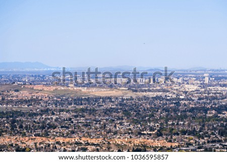 Aerial view of downtown San Jose on a clear day; residential neighborhoods in the foreground; San Francisco visible in the background; Silicon Valley, California
