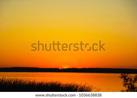 Background of water at sunset against a background of an orange lake and orange sky and cane silhouett 