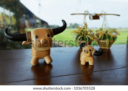 smiling wooden toy water buffaloes in front of decorative mini rice baskets