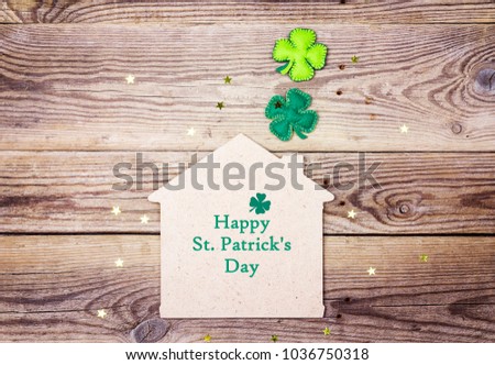 St.Patrick's day greeting message with lucky home symbol and four-leaf clover on wooden background. St.Patrick's day holiday symbol. 