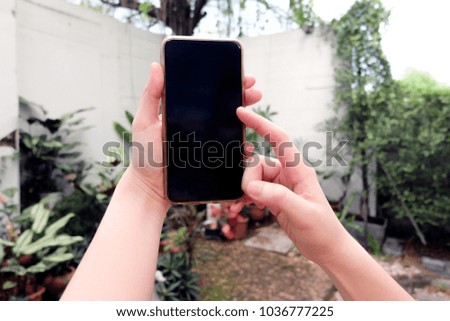 Hand holding a smart phone with black screen on natural background.
