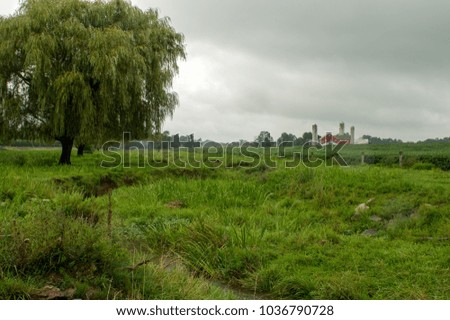 A pasture with a farm in the background surrounded by fields.