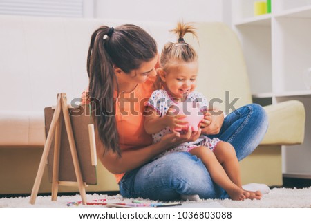 Mother is teaching her daughter how to save money.  Royalty-Free Stock Photo #1036803088