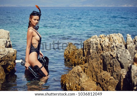Portrait of beautiful girl in shallow water with diving mask on her head, hot attractive brunette in sea with diving mask