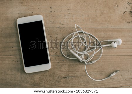White mobile phone earphone wooden background