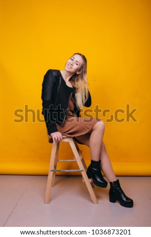 young cheerful girl with different hair color in light spring dress and leather jacket posing on paper background. emotional portrait of a student in autumn boots. long hair and clean skin
