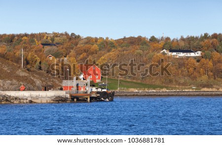 Autumn Norwegian landscape, red wooden houses near pier on seacoast