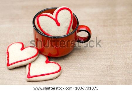 Red cup with lovely cooki in heart shape. Love biscuit for good start up.Copy space for text on card.
