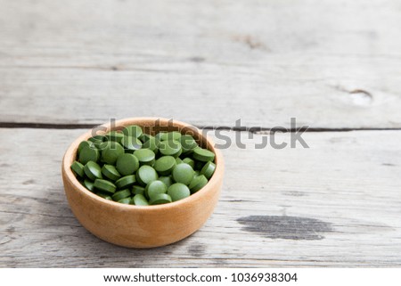 green pills spirulina or chlorella seaweed in the wooden bowl. green barley chlorella.