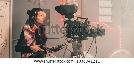 Behind the scene. Female cameraman shooting the film scene with camera in film studio Royalty-Free Stock Photo #1036941211