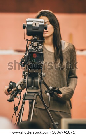 Behind the scene. Female cameraman shooting the film scene with camera in film studio