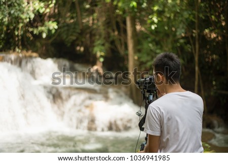 Photographer taking photo scene of Beautiful waterfall in the deep forest, huay mae khamin waterfall, Kanchanaburi province, thailand, Nature travel concept