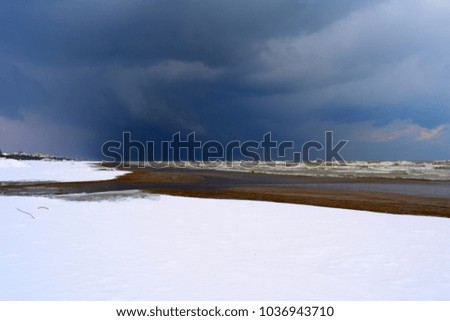 snow on the beach near the sea coast under the passage of a cold storm