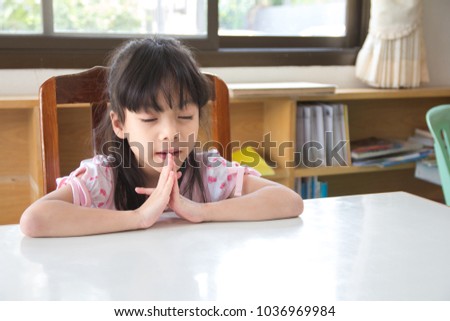 Little Asian girl sitting and praying with her friends.Little asian girl hand praying,Hands folded in prayer concept for faith,spirituality and religion.