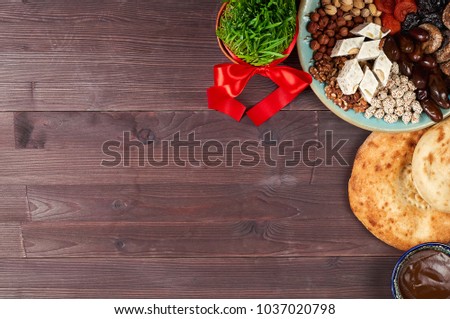 Traditional Azerbaijan sweet cuisine of holiday Nowruz: national dessert called Sumalak, lavash bread, halva, assortment of nuts and dry fruits. Sprouted seeds with red ribbon. Top view, copy space