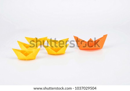 Leadership concept with a orange paper ship leading among yelllow ships