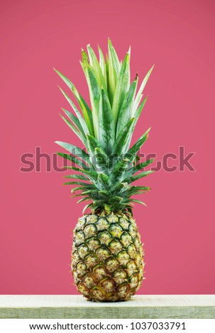 Pineapple on wooden with pink background.