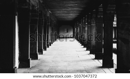 An empty corridor with pillars portrayed in black and white belonging to an old Indian Fort.