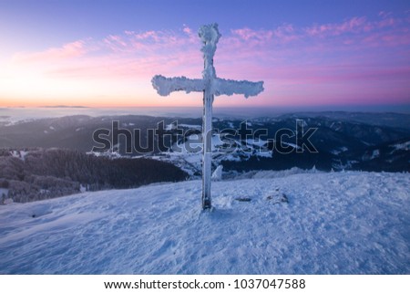 Amazing colorful sunrise over the village with cross at the top of mountain in freeze winter,beautiful background Zvolen, Big Fatra, Slovakia