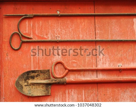 Fragment of an old wooden fire shield with a shovel and iron hooks.