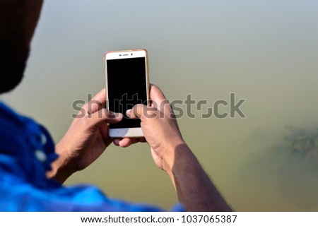 Picture of a person holding his smart phone taken from back side.